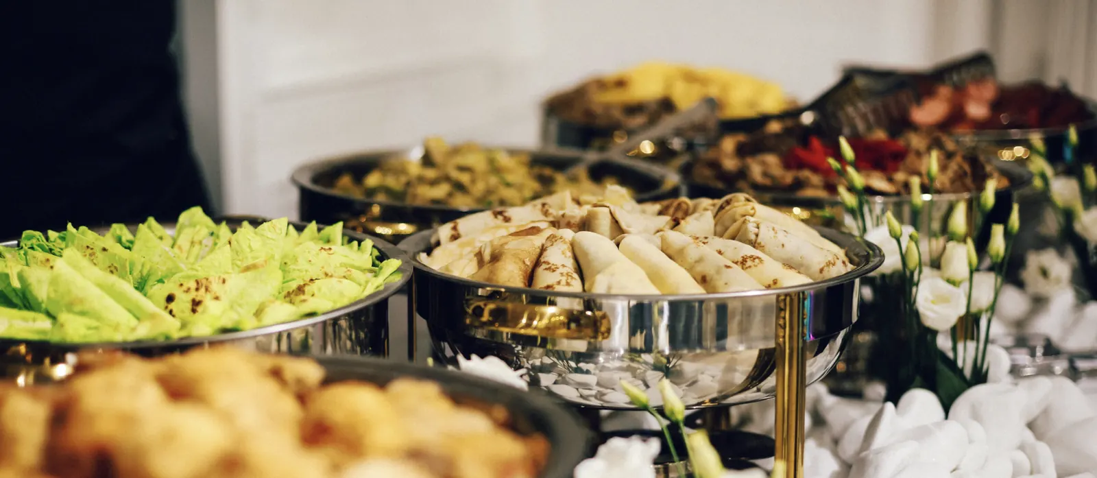 Catering buffet with wraps, salads, and hot trays by Sam & Jack's
